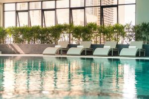 a swimming pool with white lounge chairs in a building at Hotel Soleil Ha Long, Trademark Collection by Wyndham in Ha Long