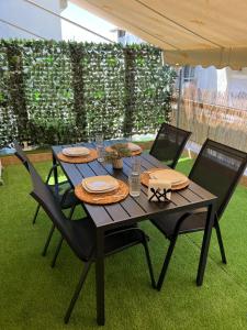 une table en bois avec des chaises, des assiettes et des verres dans l'établissement Green Oasis Apartment, à Alexandroúpolis