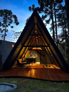 een huis met een rieten dak en een houten terras bij Chalé Villa Nature in Campos do Jordão