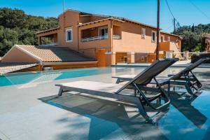 une piscine avec deux chaises longues et une maison dans l'établissement Pyramid City Apartments, à Agios Spyridonas