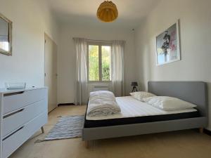 a bedroom with a bed and a dresser and a window at CAPELAN in Bandol