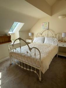 ein weißes Bett in einem Zimmer mit Fenster in der Unterkunft Escape to a Cosy Country Barn: Discover the Charm of Rustic Living 