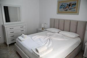 ドゥラスにあるGimi Apartments 1のタオルが敷かれた白いベッドのある寝室