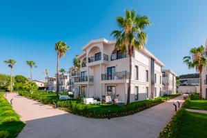 a large white building with palm trees in front of it at Benata Beach Hotel Ultra All Inclusive in Manavgat