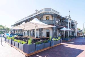 Un edificio con mesas y sombrillas delante. en The Sea Haven 200m to Henley Beach, en Henley Beach South