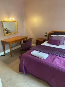 a bedroom with a bed and a table and a mirror at The Royal Victoria & Bull Hotel in Rochester