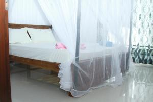 a bed with white curtains in a room at A2+villa in Weligama