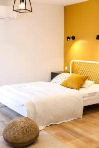 1 dormitorio con cama blanca y pared amarilla en Studio cosy équipé, Centre ville en Orange