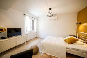 1 dormitorio blanco con 1 cama y TV en Studio cosy équipé, Centre ville en Orange