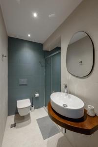 a bathroom with a sink and a toilet and a mirror at Galio Suites Airport by Airstay in Spáta