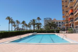 une piscine avec des palmiers en face d'un hôtel dans l'établissement Playa Dorada, à Peñíscola