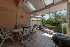 Un patio con sillas, una mesa y una sombrilla. en Holiday Home Cosy Summer, en Karigador 35 fotos más
