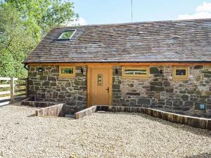 a stone house with a wooden door and a yard at Stunning cottage nestled under the Longmynd Hills. in Church Stretton