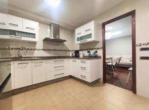 a kitchen with white cabinets and a dining room at Casa-Nova Centro in Sarria