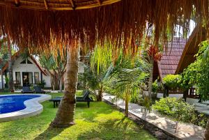 a resort yard with a pool and a straw umbrella at Gili Land in Gili Islands