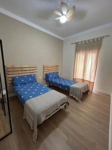 een slaapkamer met 2 bedden en een plafondventilator bij El corazon de la Luna in Badajoz