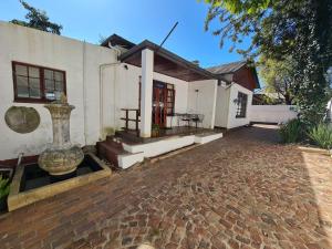 Uma casa branca com uma entrada de tijolos à frente. em Melville House em Joanesburgo