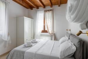 a white bedroom with a bed with two towels on it at Osvaldo - parcheggio e giardino privato in San Giovanni in Persiceto
