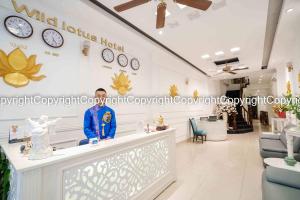 a man standing at a counter in a store with clocks on the wall at Wild Lotus Hotel & Travel 2 in Hanoi