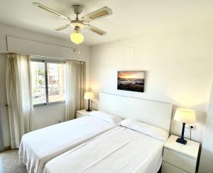 a white bedroom with a bed and two lamps at Apartamentos Ulia in Benidorm