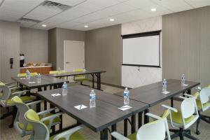 a conference room with tables and chairs and a white screen at SpringHill Suites by Marriott Jacksonville Baymeadows in Jacksonville