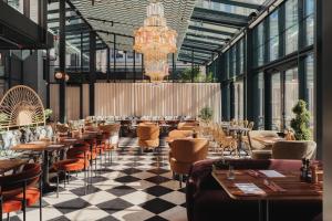 a restaurant with tables and chairs and a chandelier at Ad Astra by Elite - Hotel, Spa & Resort in Södertälje