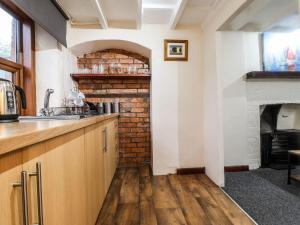 a kitchen with a brick wall and a fireplace at Cosy seaside town cottage with private garden in Cardigan