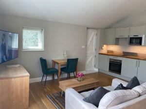 a living room with a white couch and a kitchen at 2 person studio flat near Richmond Park in Strawberry Hill