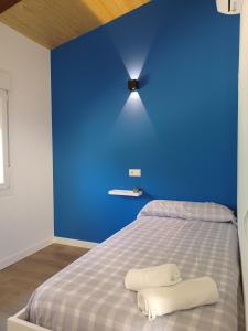 Una pared azul con una cama con dos toallas. en Bungalow Sierra San Vicente, en Hinojosa de San Vicente