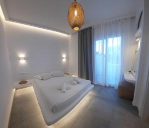 a white bedroom with a large white bed and a window at Paros Blue Dolphin FULLY RENOVATED by RIVEA GROUP in Chrissi Akti