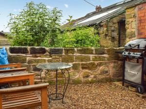 a patio with a table and a brick wall at Weavers Cottage in Barnsley