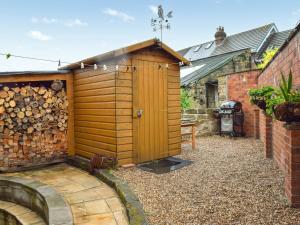 ein Holzhaus mit einer Holztür im Hof in der Unterkunft Weavers Cottage in Barnsley