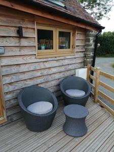 a deck with two wicker chairs and a cabin at Cosy and quiet one bed barn conversion. in Church Stretton