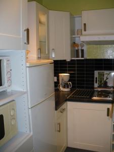 eine Küche mit weißen Geräten und schwarzen Fliesen in der Unterkunft Les Bastides in Gréoux-les-Bains