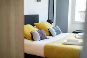 a bedroom with a bed with yellow and blue pillows at Le Kador, appartement avec vue sur mer in Crozon