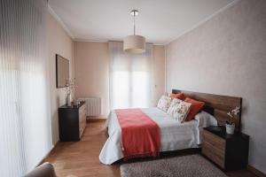 una camera con un letto con una coperta rossa di Chalet Os castaños a Caldas de Reis