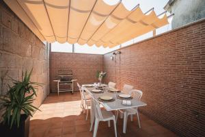 un patio con tavolo, sedie e muro di mattoni di Chalet Os castaños a Caldas de Reis