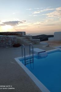 una piscina azul con puesta de sol en el fondo en Villa Elliah, en Episkopianá
