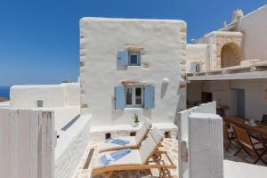 una casa blanca con ventanas azules y sillas en el techo en Villa Elliah, en Episkopianá