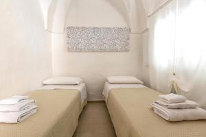 2 Betten in einem Zimmer mit weißen Wänden in der Unterkunft Vico dei Mille by BarbarHouse in Tuglie