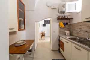 eine Küche mit weißen Schränken und einem Holztisch in der Unterkunft Vico dei Mille by BarbarHouse in Tuglie