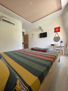 クイニョンにあるÁnh Dươngのベッドルーム1室(カラフルなストライプ毛布付きのベッド1台付)