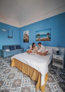 a man and a woman sitting on a bed at La Bifora e il granaio in Sciacca