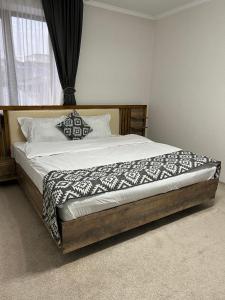 a bed with a wooden frame in a bedroom at Cube House Osh in Osh