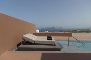 einen Pool mit einer Chaiselongue an der Seite eines Hauses in der Unterkunft Serra Exclusive Suites in Akrotiri