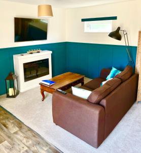 sala de estar con sofá marrón y chimenea en Cariad Bach en Llandudno