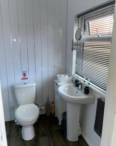Baño blanco con aseo y lavamanos en Cariad Bach en Llandudno