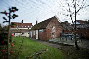 ein Haus mit einem Tisch und Stühlen im Hof in der Unterkunft White Horse Cottage with Sauna in Ollerton