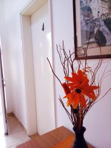 a vase with a orange flower on a table at Apartmani SAMB Igalo in Herceg-Novi
