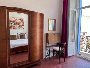 a room with a bedroom with a bed and a mirror at Abri du vent, chambres et appartements in Fitou